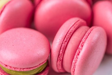 Makarnalar beyaz ahşap arka planda yakınlaşır. Tatlı ve renkli pembe Fransız badem kurabiyeleri. Evde yemek pişirmek.. 