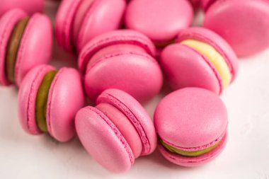 Makarnalar beyaz ahşap arka planda yakınlaşır. Tatlı ve renkli pembe Fransız badem kurabiyeleri. Evde yemek pişirmek.. 