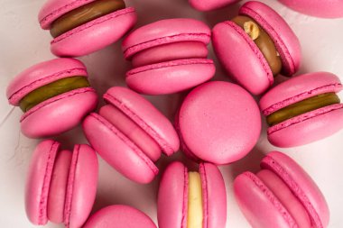 Makarnalar beyaz ahşap arka planda yakınlaşır. Tatlı ve renkli pembe Fransız badem kurabiyeleri. Evde yemek pişirmek.. 