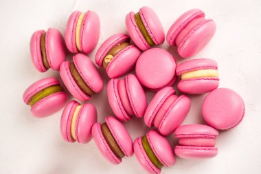 Makarnalar beyaz ahşap arka planda yakınlaşır. Tatlı ve renkli pembe Fransız badem kurabiyeleri. Evde yemek pişirmek.. 