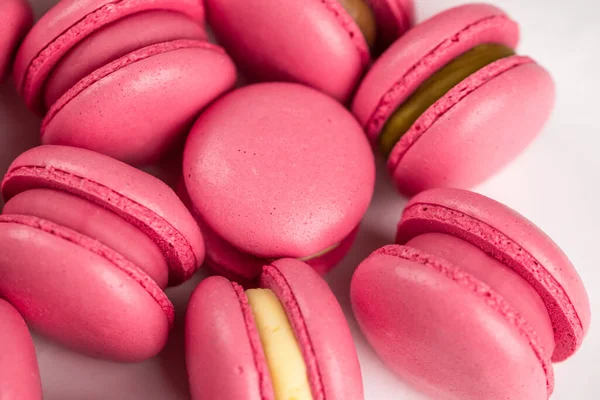 Makarnalar beyaz ahşap arka planda yakınlaşır. Tatlı ve renkli pembe Fransız badem kurabiyeleri. Evde yemek pişirmek.. 