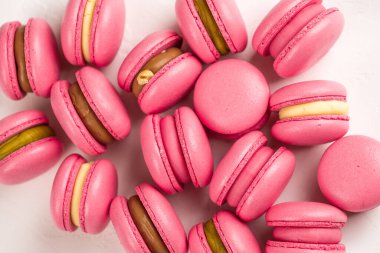 Makarnalar beyaz ahşap arka planda yakınlaşır. Tatlı ve renkli pembe Fransız badem kurabiyeleri. Evde yemek pişirmek.. 