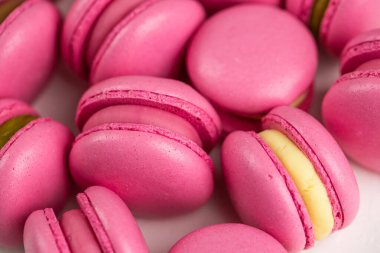 Makarnalar beyaz ahşap arka planda yakınlaşır. Tatlı ve renkli pembe Fransız badem kurabiyeleri. Evde yemek pişirmek.. 