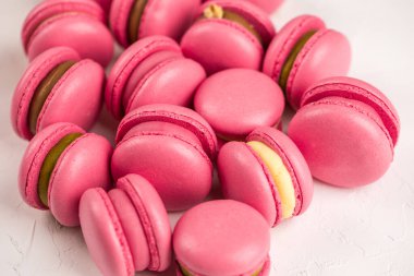 Makarnalar beyaz ahşap arka planda yakınlaşır. Tatlı ve renkli pembe Fransız badem kurabiyeleri. Evde yemek pişirmek.. 