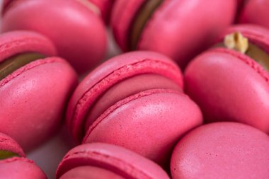 Makarnalar beyaz ahşap arka planda yakınlaşır. Tatlı ve renkli pembe Fransız badem kurabiyeleri. Evde yemek pişirmek.. 