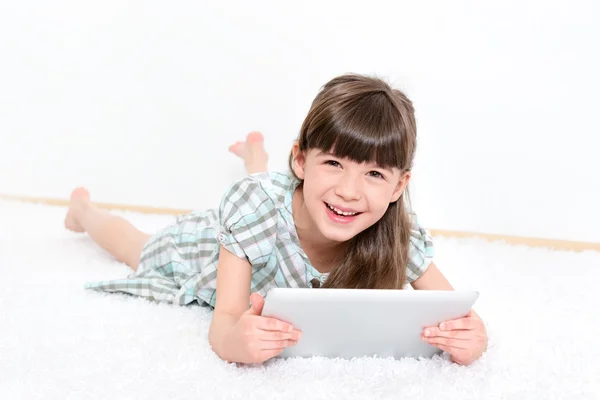 Fröhliches kleines Mädchen mit einem Tablet — Stockfoto