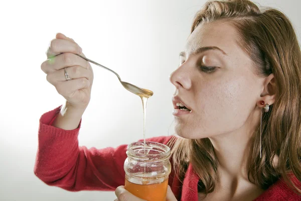 Jonge vrouw eten van honing — Stockfoto