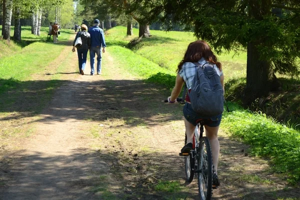 Девушка ездит на велосипеде по летнему парку — стоковое фото