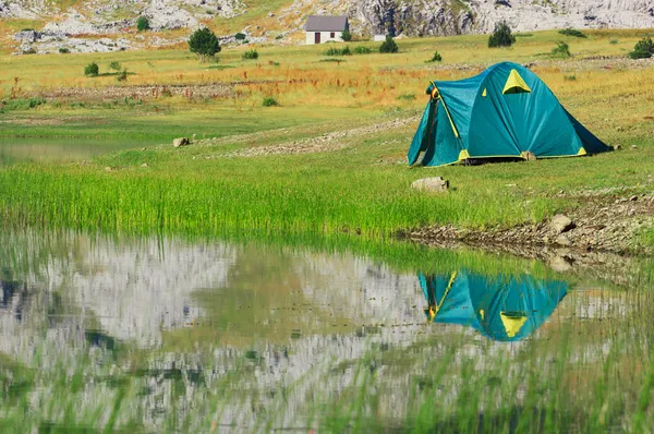 Tourist tent stands on the green meadow near the lake — Stock Photo, Image