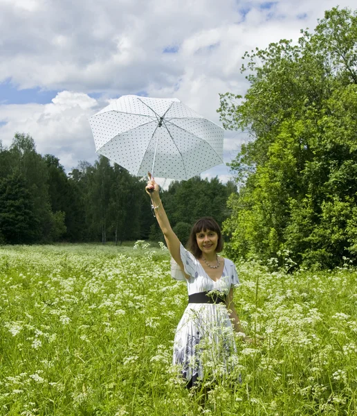Jonge vrouw met witte paraplu op weide in bloei — Stockfoto