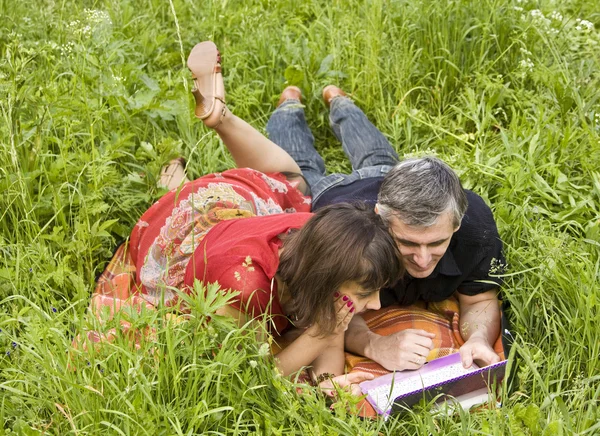 Пара с ноутбуком на траве — стоковое фото