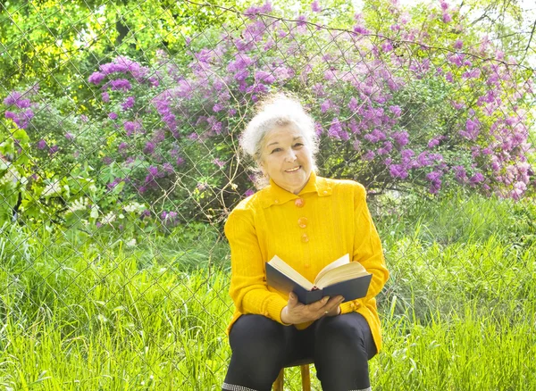 Gammal dam läsande i trädgården — Stockfoto