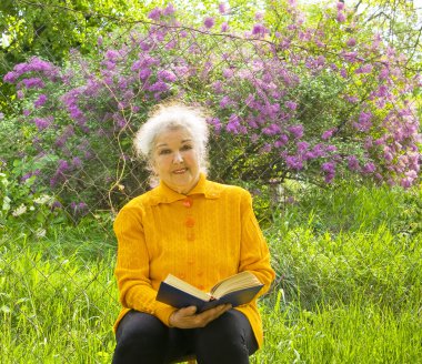 yaşlı kadın bahçede kitap okumak