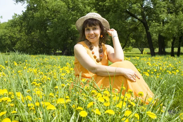 Vrouw in hoed met gele paardebloemen — Stockfoto