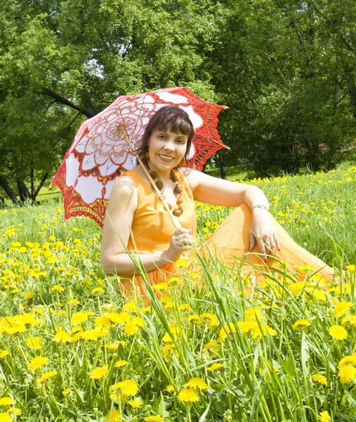 Vrouw met paraplu op weide met paardebloemen — Stockfoto