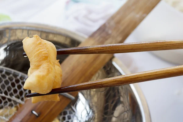 Bamboo chopsticks holding deep-fried dough stick — Stock Photo, Image