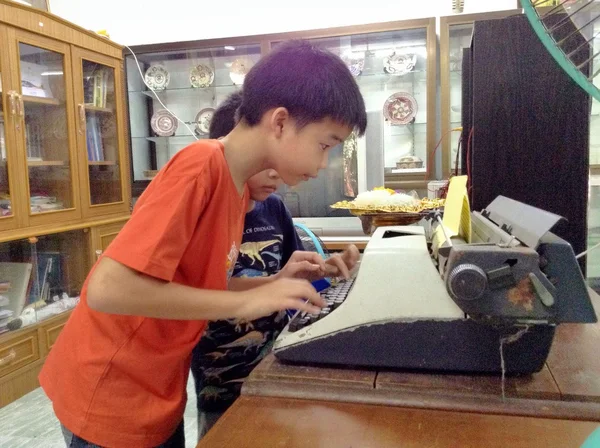 タイプライターまたは耕す」機械を使用する方法を学ぶタイの男の子. — ストック写真
