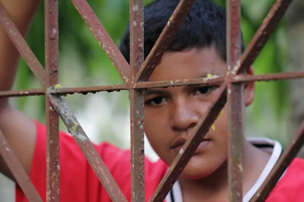 Niño detrás de una rejilla de hierro — Foto de Stock