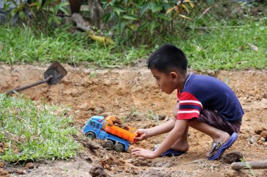 Asian Thai little boy play plastic truck in the backyard
