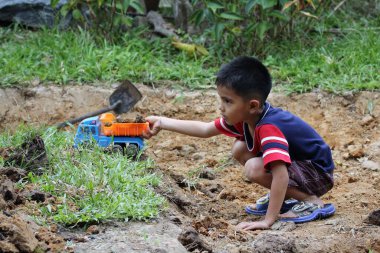 Asian Thai little boy play plastic truck in the backyard