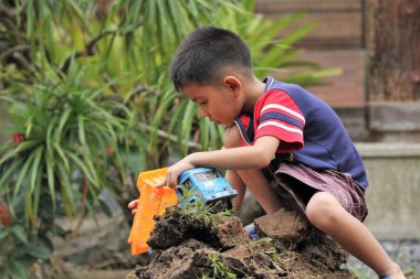 Asian Thai little boy play plastic truck in the backyard