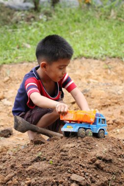 Asian Thai little boy play plastic truck in the backyard