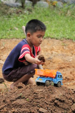 Asian Thai little boy play plastic truck in the backyard