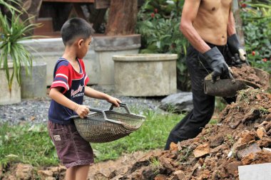 Asian boy pours soil from a bucket