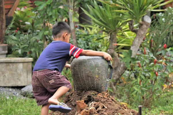 Asian boy pours soil from a bucket