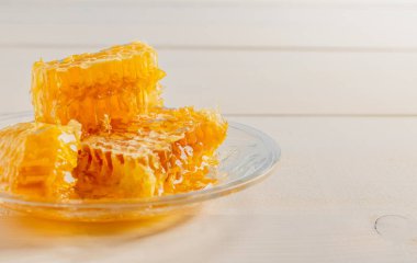 Cam tabakta taze bal olan bal peteği. Beyaz tahta arkaplan.