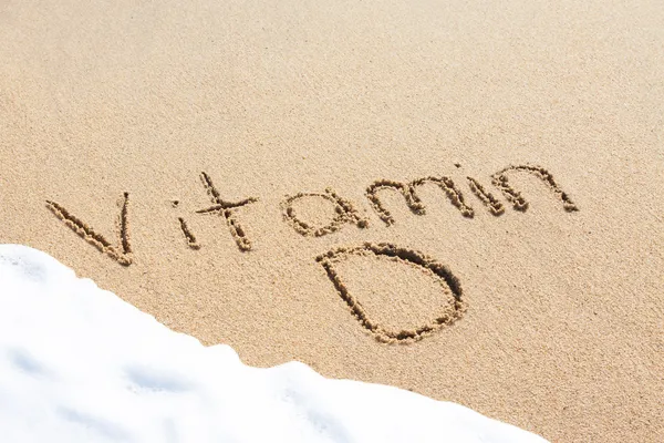 Vitamina D escrita en la arena — Foto de Stock