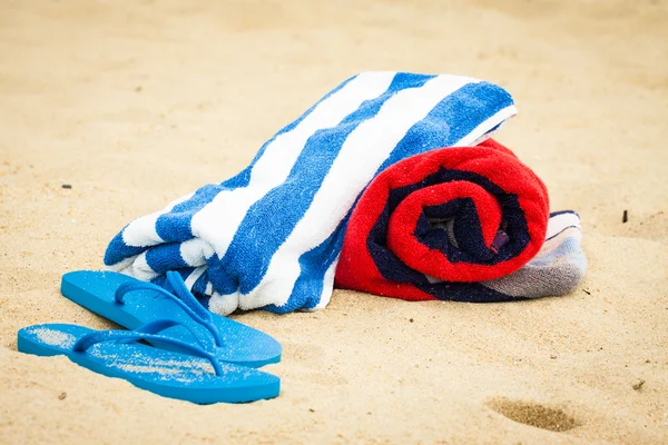 Serviette de plage et sandales sur la plage Photo De Stock