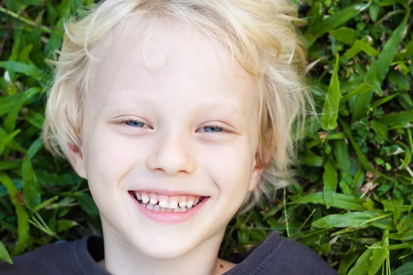 Smiling young boy lying in grass smiling — Stock Photo, Image