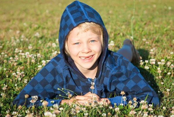 Smiling young boy lying in grass smiling — Stock Photo, Image