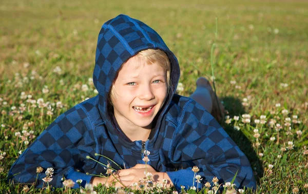 Šťastný chlapec ležící v trávě s úsměvem — Stock fotografie