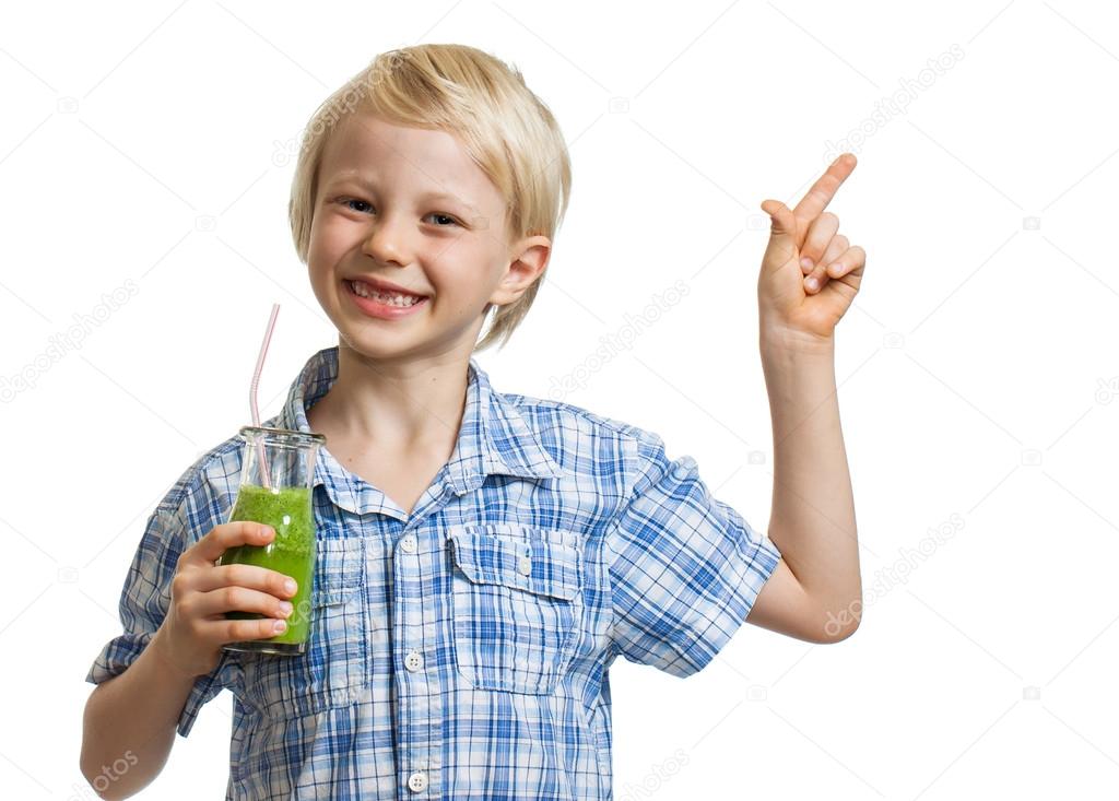 Cute boy holding green smoothie and pointing