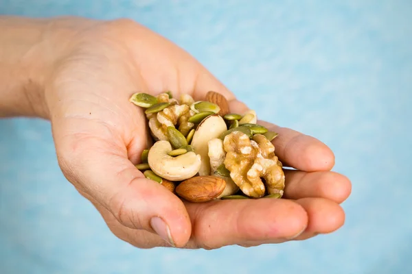 Hand met een verscheidenheid van noten en zaden — Stockfoto