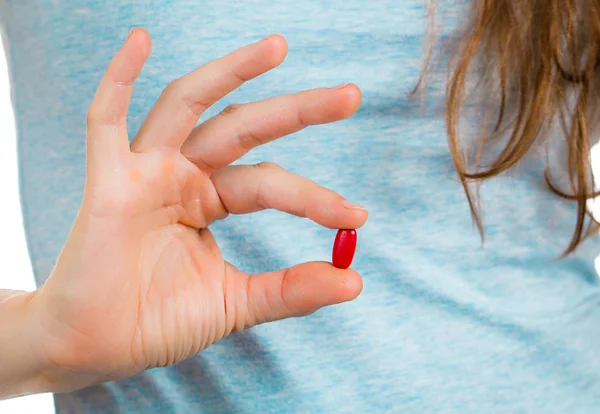 Dedos sosteniendo una píldora roja . — Foto de Stock