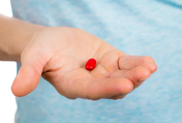 Primer plano de la mano sosteniendo una píldora roja . —  Fotos de Stock