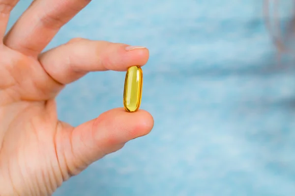 Close-up of fingers holding a fish oil capsule. — Stock Photo, Image