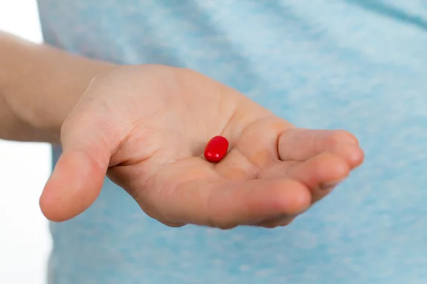 Primer plano de la mano sosteniendo una píldora roja . — Foto de Stock
