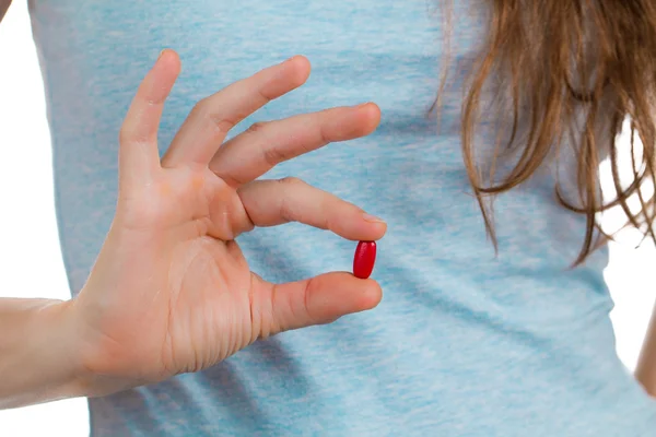 Doigts tenant une pilule rouge . Photo De Stock