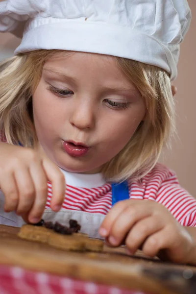 Mignon jeune garçon mettre raisins secs sur pain d'épice — Photo