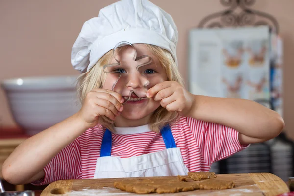 Bonito menino sorridente espreitando através de cortador de biscoitos — Fotografia de Stock