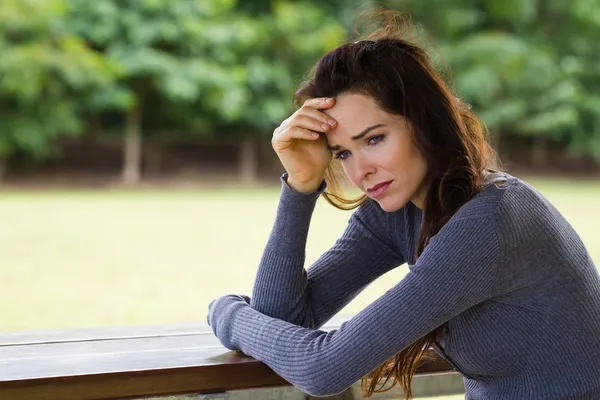 屋外に座っている悲しいと心配の女性 ストック画像