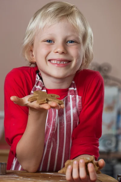 Smiling proud boy holding up gingerbread man — Stock Photo, Image