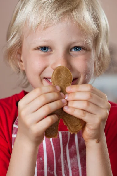 Close-up of cute boy holding up gingerbread man — Stock Photo, Image