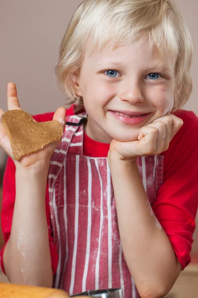 Cute boy holding up gingerbread love heart — Stock Photo, Image