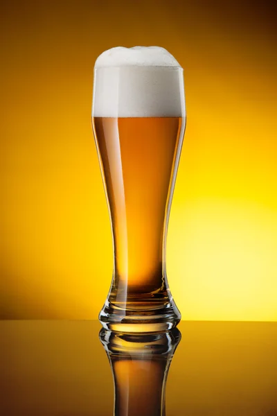 Glas Bier auf gelbem Hintergrund Stockbild