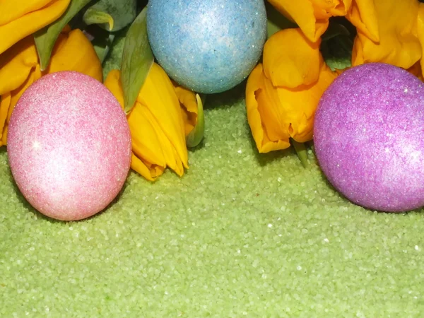 Colorful easter eggs with yellow flower in green stones — Stock Photo, Image